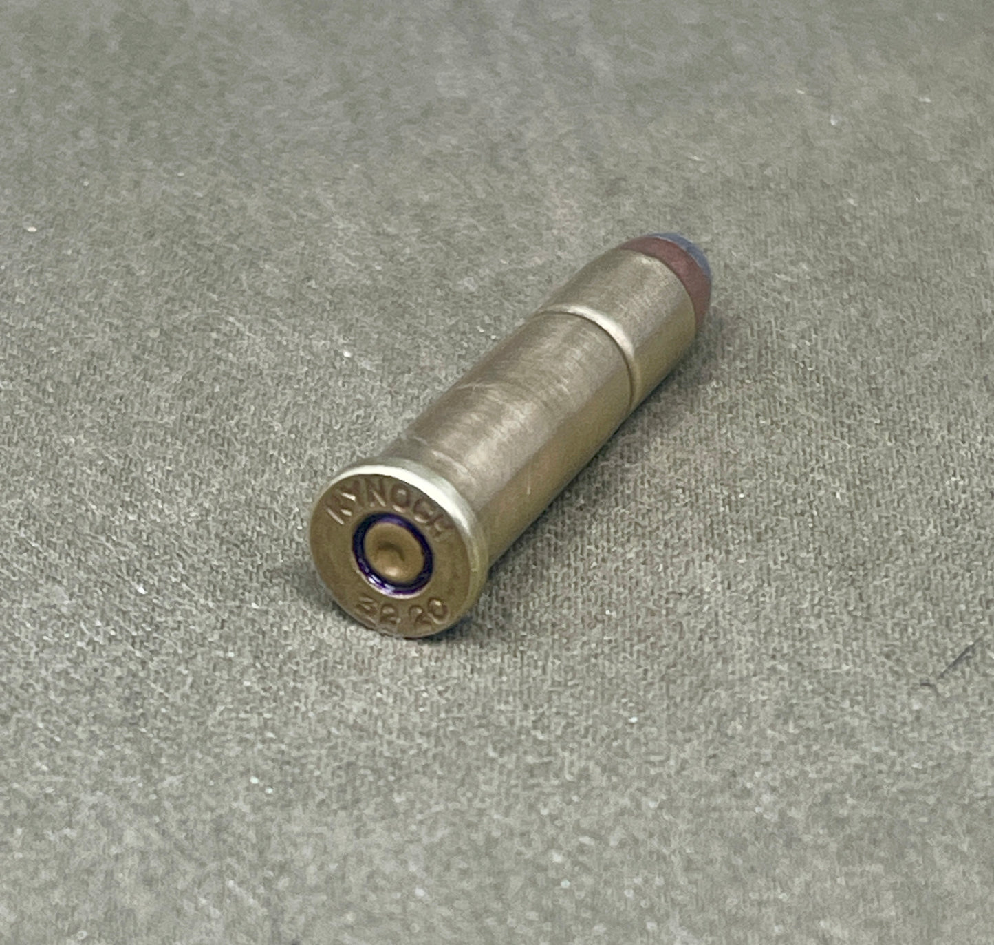 Metallic bullet casing on a textured gray surface