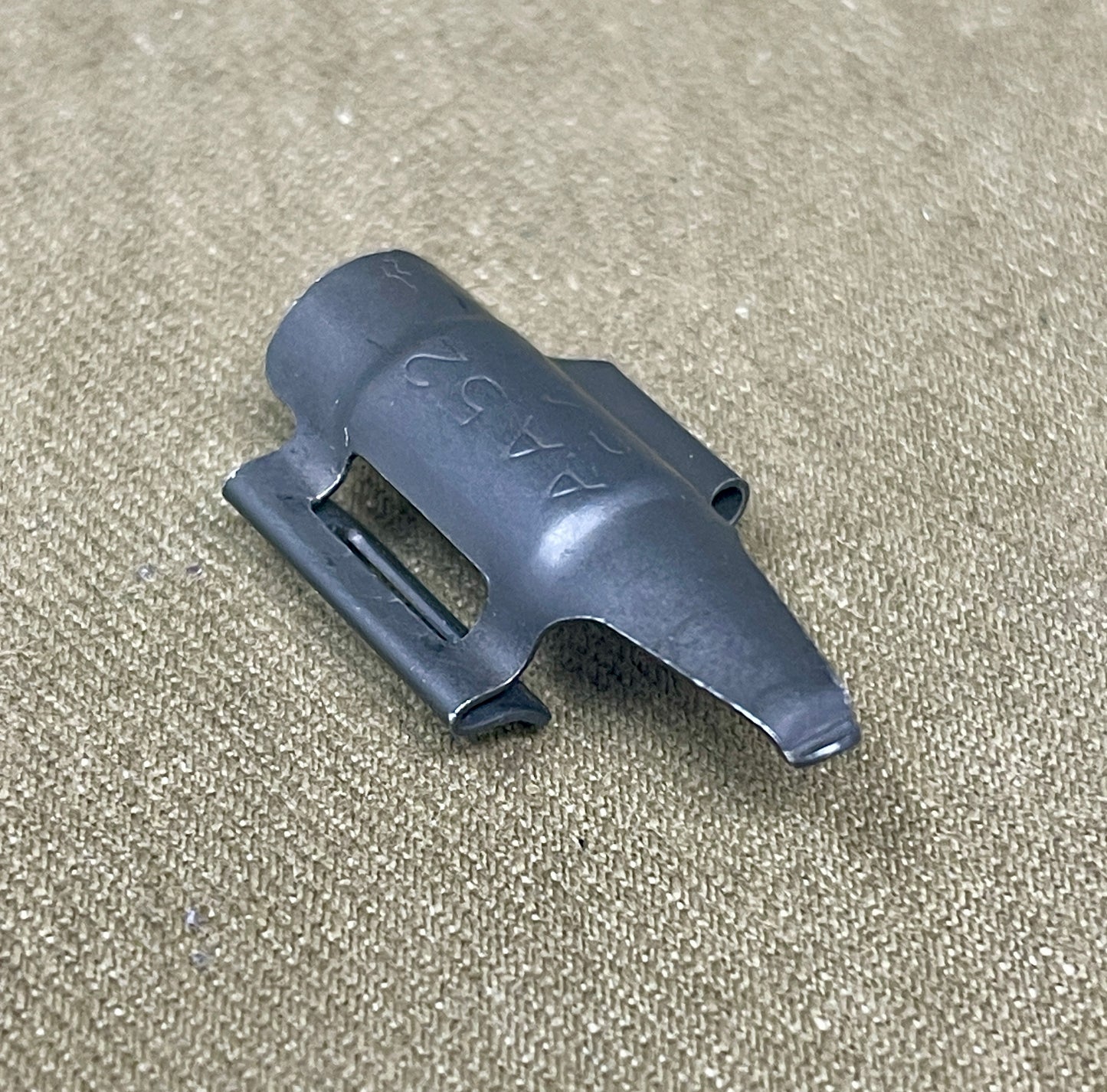 Black plastic component on a beige fabric background
