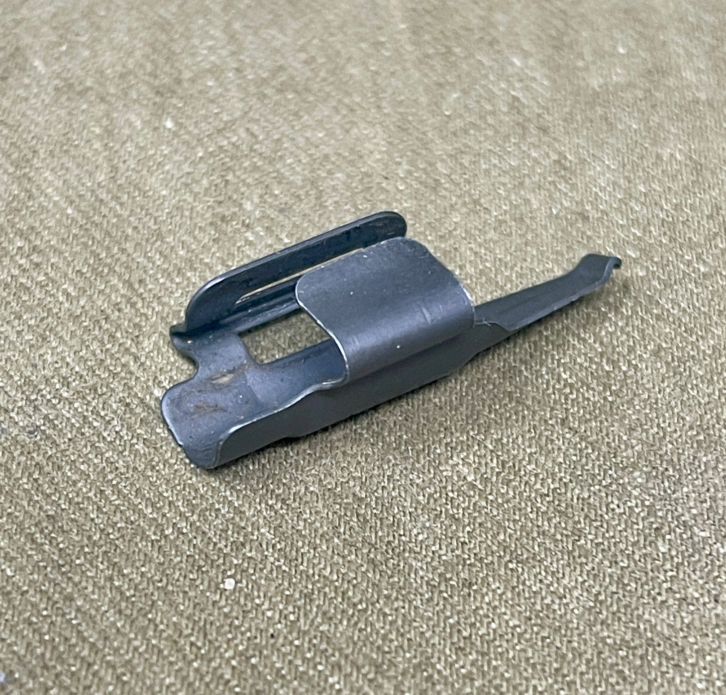 Black plastic component on a beige textured background