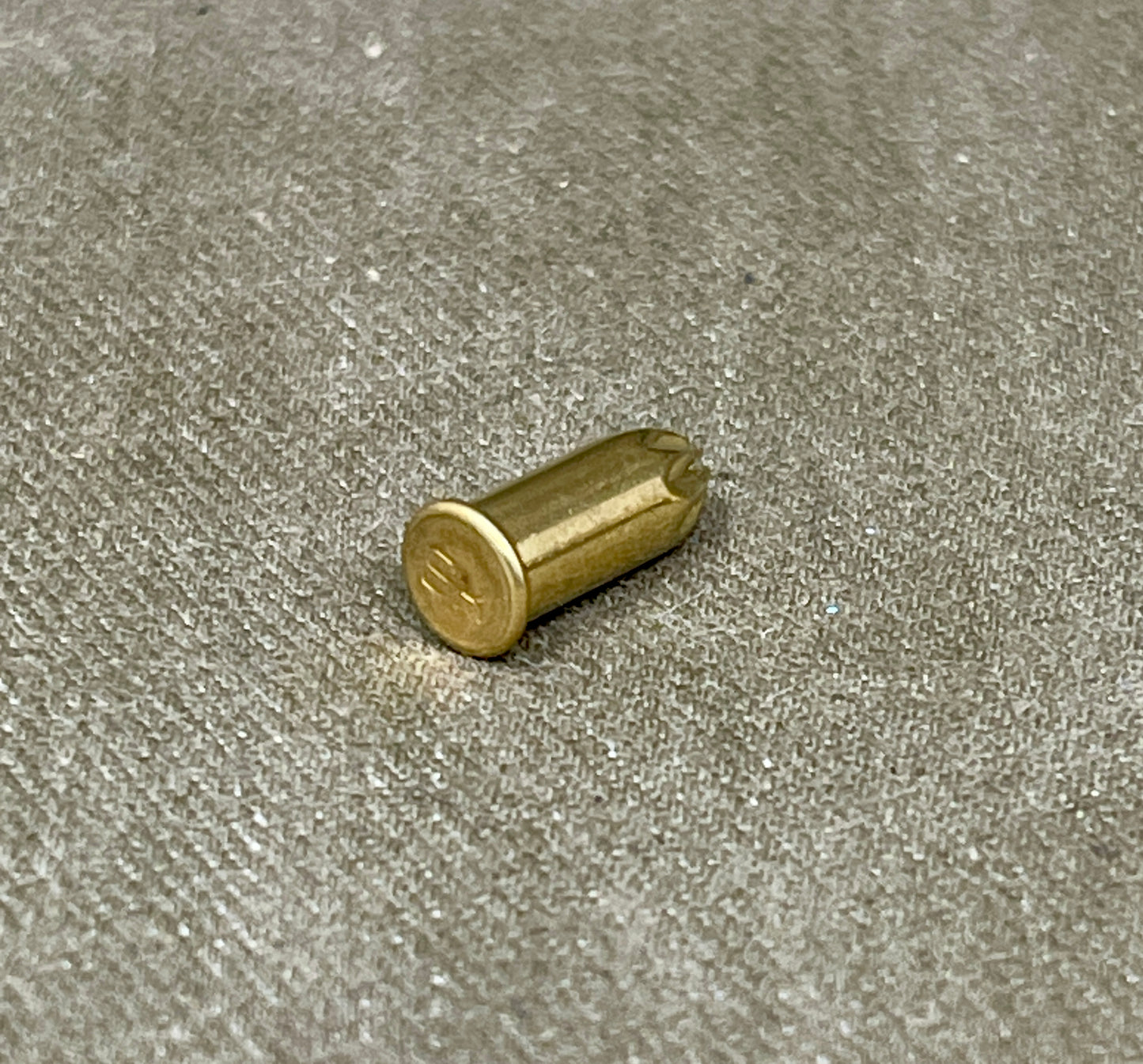 Brass cylindrical object on a textured gray surface
