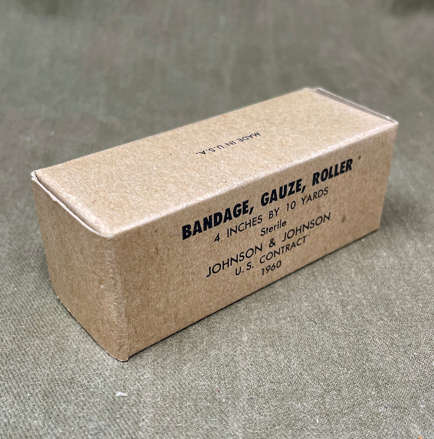 The U.S. Army Bandage, Gauze, Roller, 4 Inch by 10 Yards, Sterile was a military-issue medical supply used for wound dressing and stabilization. Manufactured by Johnson & Johnson under a U.S. government contract in 1960, this sterile gauze bandage was essential for treating injuries in field conditions.
Measuring 4 inches wide and 10 yards long, the bandage was designed for versatility in wound management, allowing medics and soldiers to wrap and secure dressings, control bleeding, and protect wounds from