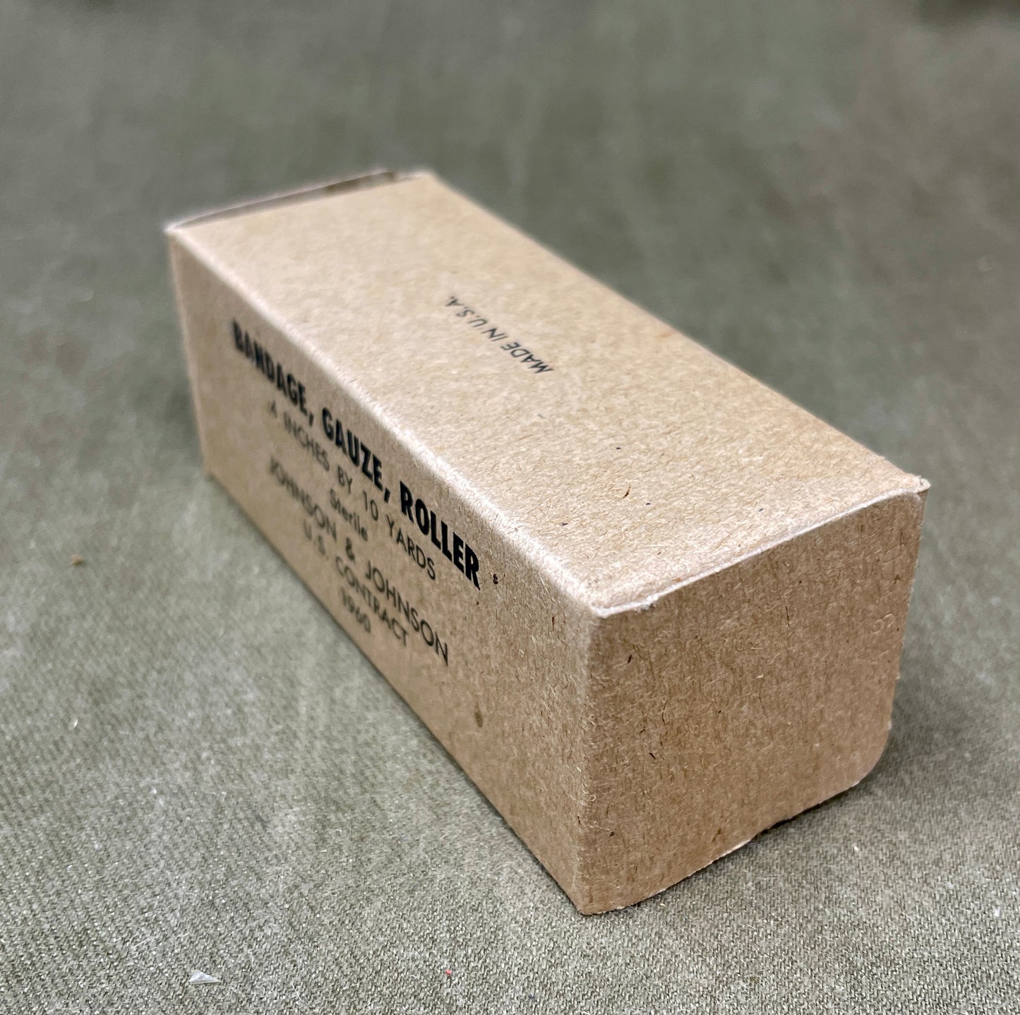 The U.S. Army Bandage, Gauze, Roller, 4 Inch by 10 Yards, Sterile was a military-issue medical supply used for wound dressing and stabilization. Manufactured by Johnson & Johnson under a U.S. government contract in 1960, this sterile gauze bandage was essential for treating injuries in field conditions.
Measuring 4 inches wide and 10 yards long, the bandage was designed for versatility in wound management, allowing medics and soldiers to wrap and secure dressings, control bleeding, and protect wounds from