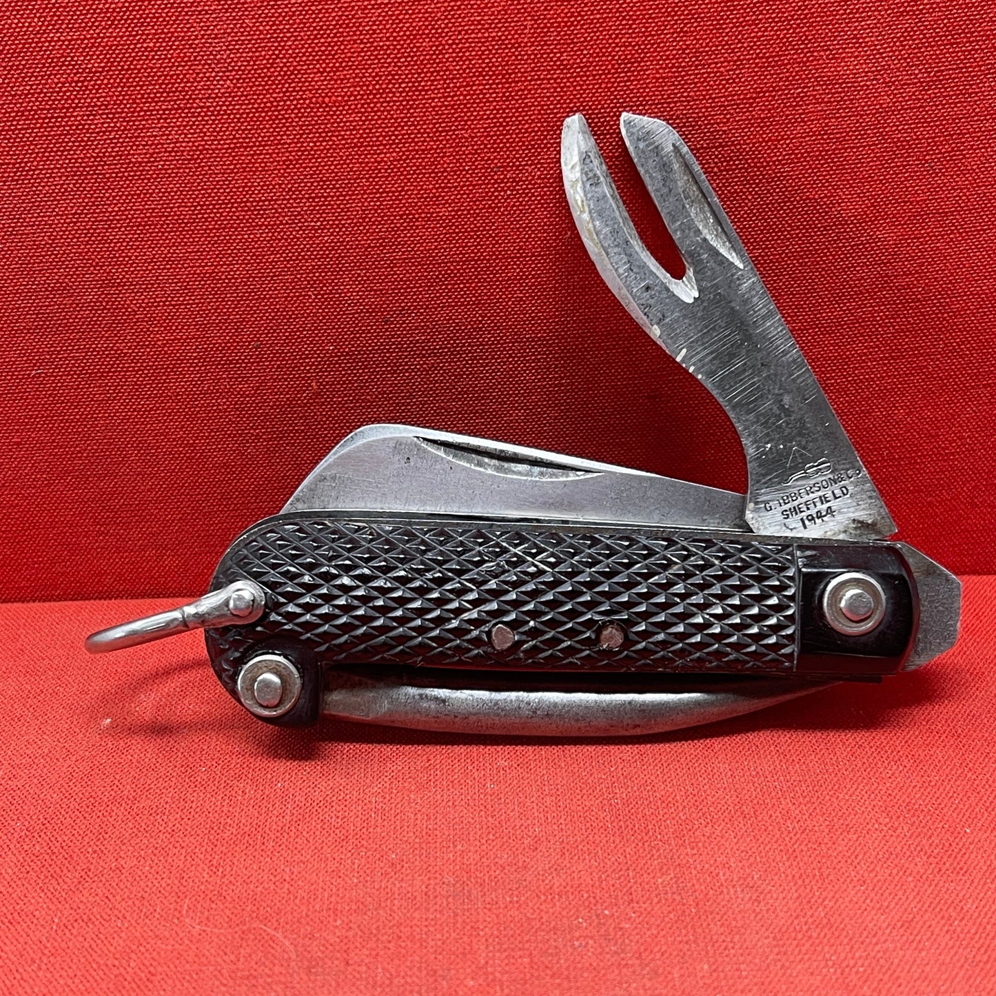 A nice example of a British 1944 Dated G Ibberson & Co military Jack Knife The blades are in good condition, the chequered Bakelite grip is intact and all the blades lock and close as they should. The steel can opener is in good condition