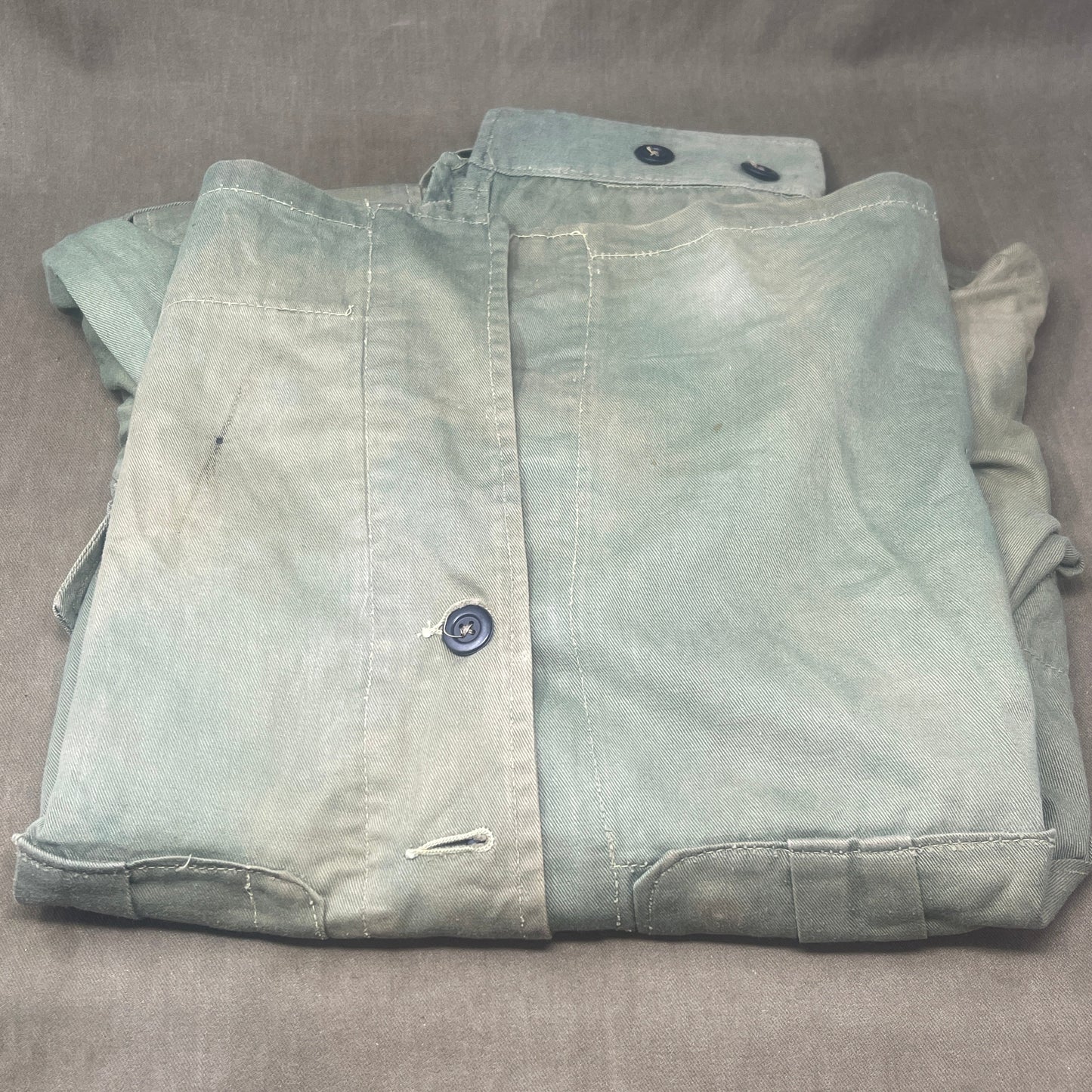 This original 1951-dated British Army Jungle Green Bush Jacket is a superb example of early post-war tropical combat clothing, manufactured by the reputable N. Lotery & Co. Ltd. Made from sturdy, breathable cotton in classic Jungle Green, this jacket was designed for use in humid and challenging environments such as Malaya and other post-war theatres of operation.
The jacket is in excellent condition, showing minimal signs of wear, with its color, stitching, and structural integrity all remarkably well-pre
