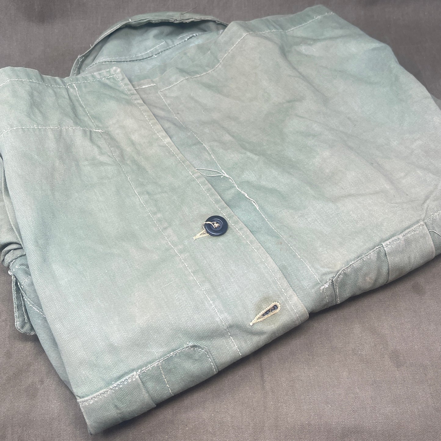 This original 1951-dated British Army Jungle Green Bush Jacket is a superb example of early post-war tropical combat clothing, manufactured by the reputable N. Lotery & Co. Ltd. Made from sturdy, breathable cotton in classic Jungle Green, this jacket was designed for use in humid and challenging environments such as Malaya and other post-war theatres of operation.
The jacket is in excellent condition, showing minimal signs of wear, with its color, stitching, and structural integrity all remarkably well-pre