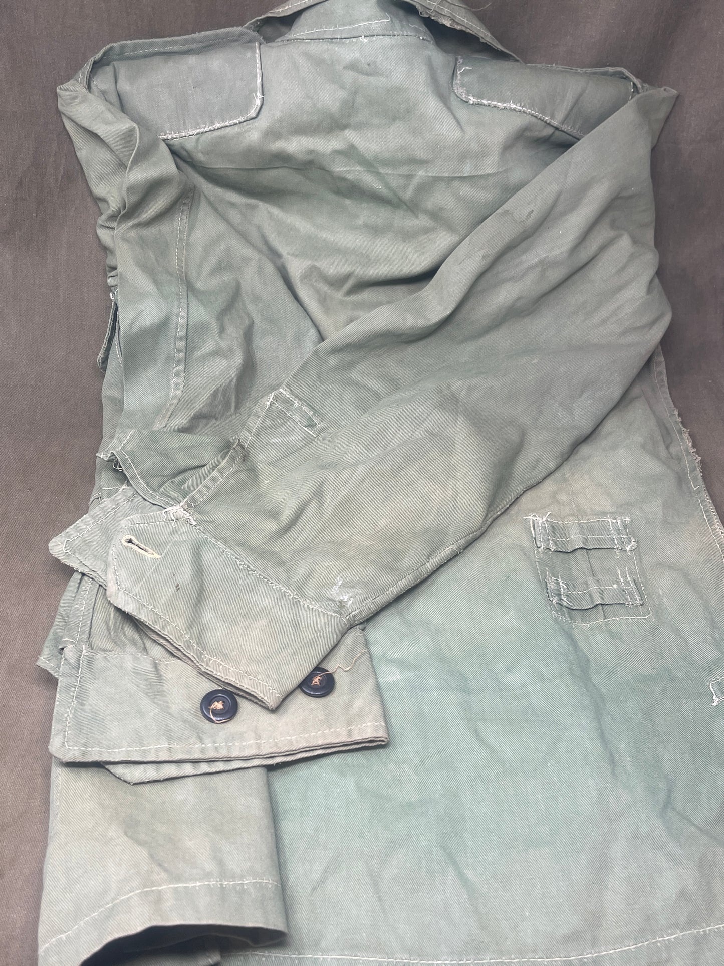 This original 1951-dated British Army Jungle Green Bush Jacket is a superb example of early post-war tropical combat clothing, manufactured by the reputable N. Lotery & Co. Ltd. Made from sturdy, breathable cotton in classic Jungle Green, this jacket was designed for use in humid and challenging environments such as Malaya and other post-war theatres of operation.
The jacket is in excellent condition, showing minimal signs of wear, with its color, stitching, and structural integrity all remarkably well-pre