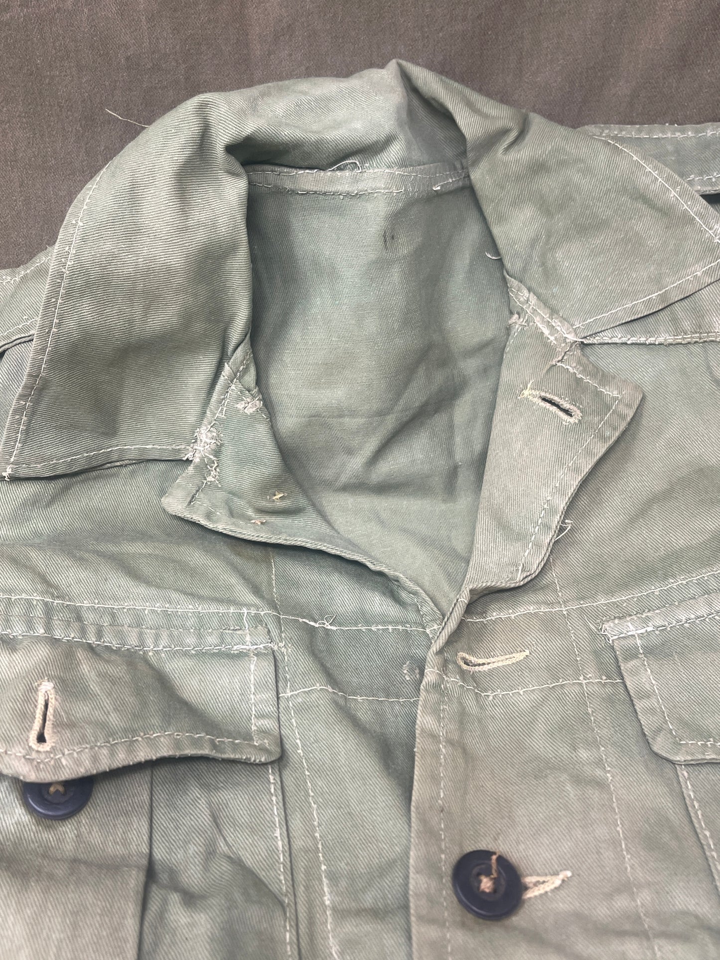 This original 1951-dated British Army Jungle Green Bush Jacket is a superb example of early post-war tropical combat clothing, manufactured by the reputable N. Lotery & Co. Ltd. Made from sturdy, breathable cotton in classic Jungle Green, this jacket was designed for use in humid and challenging environments such as Malaya and other post-war theatres of operation.
The jacket is in excellent condition, showing minimal signs of wear, with its color, stitching, and structural integrity all remarkably well-pre