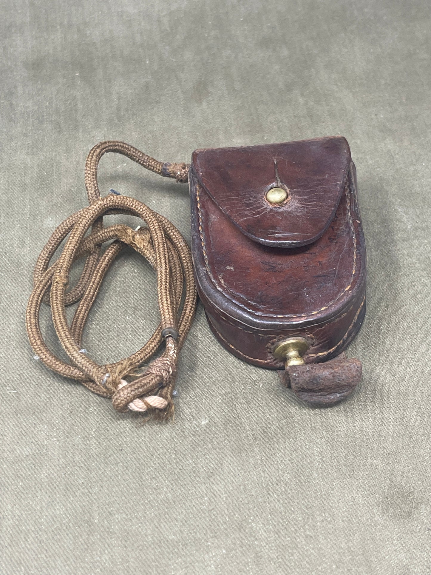 This original British Military Prismatic Compass Mk III, dated 1940 and stamped with serial number NA266322, is an exceptional artifact from the Second World War. Manufactured by TG Co Ltd, a recognized wartime supplier, this compass is a classic example of durable British military engineering.
The Mk III model features a solid brass case, often finished in matte black or olive drab, designed to withstand the rigors of field use. Its prismatic sighting mechanism allows for highly accurate bearings, even in