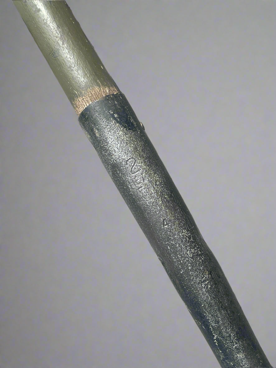 Close-up of a garden tool handle with a brand name on a concrete surface