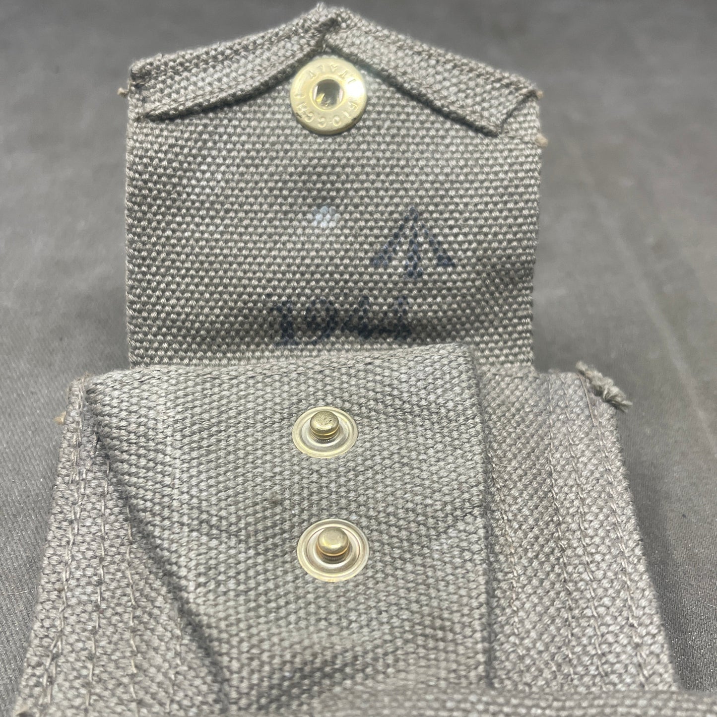 Close-up of a gray fabric pocket with buttons on a dark background