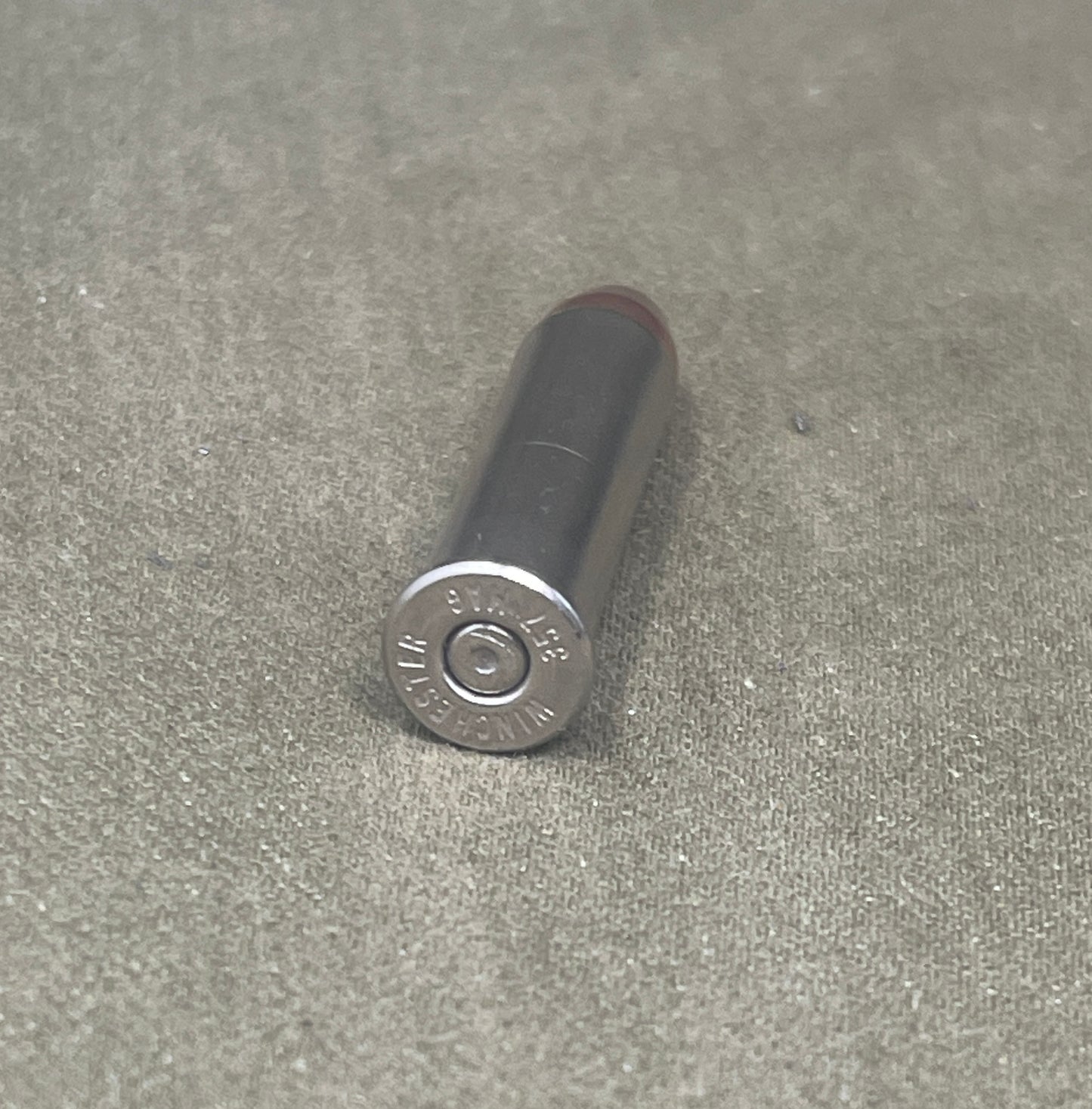 Black cylindrical object with metallic cap on a gray concrete surface