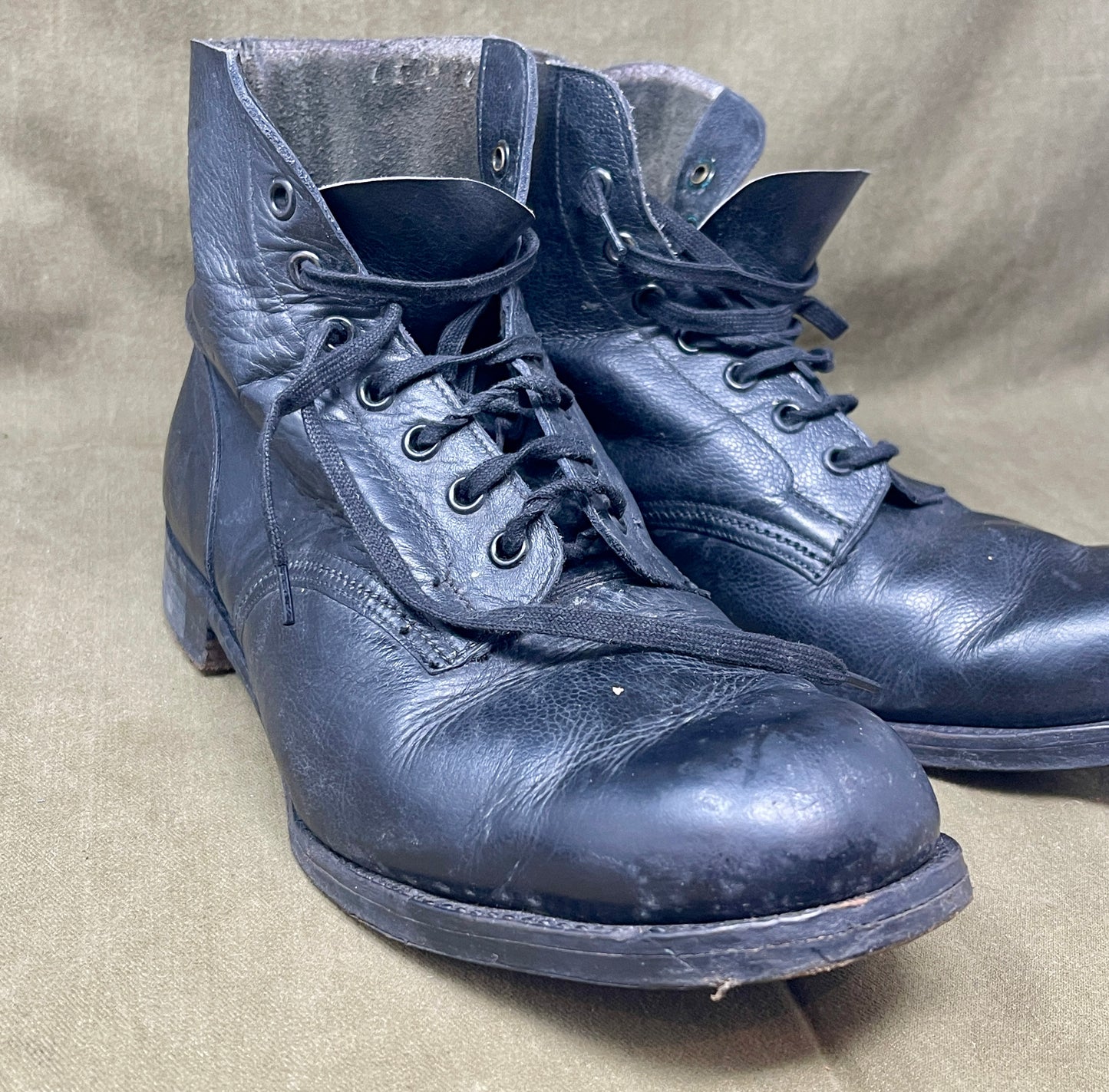 Pair of worn blue leather boots on a beige background