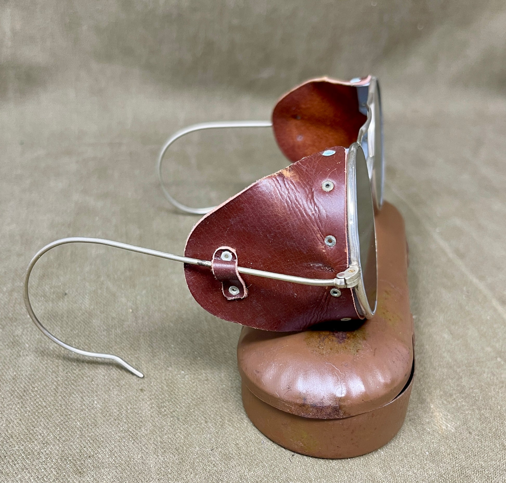 Pair of sunglasses with brown leather cases on a beige background