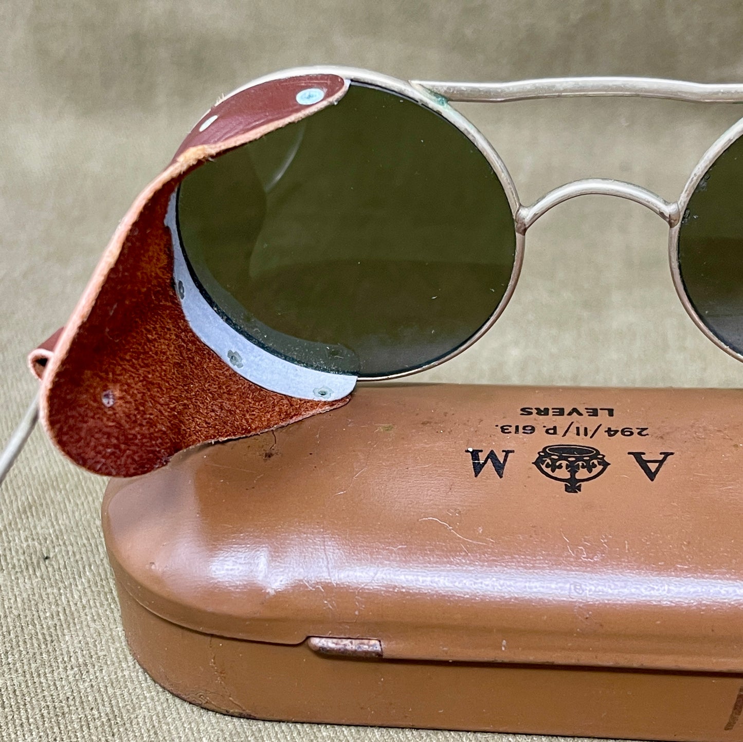 Round sunglasses with a brown case on a beige fabric background
