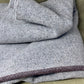 Gray textured fabric with a purple trim on a beige surface