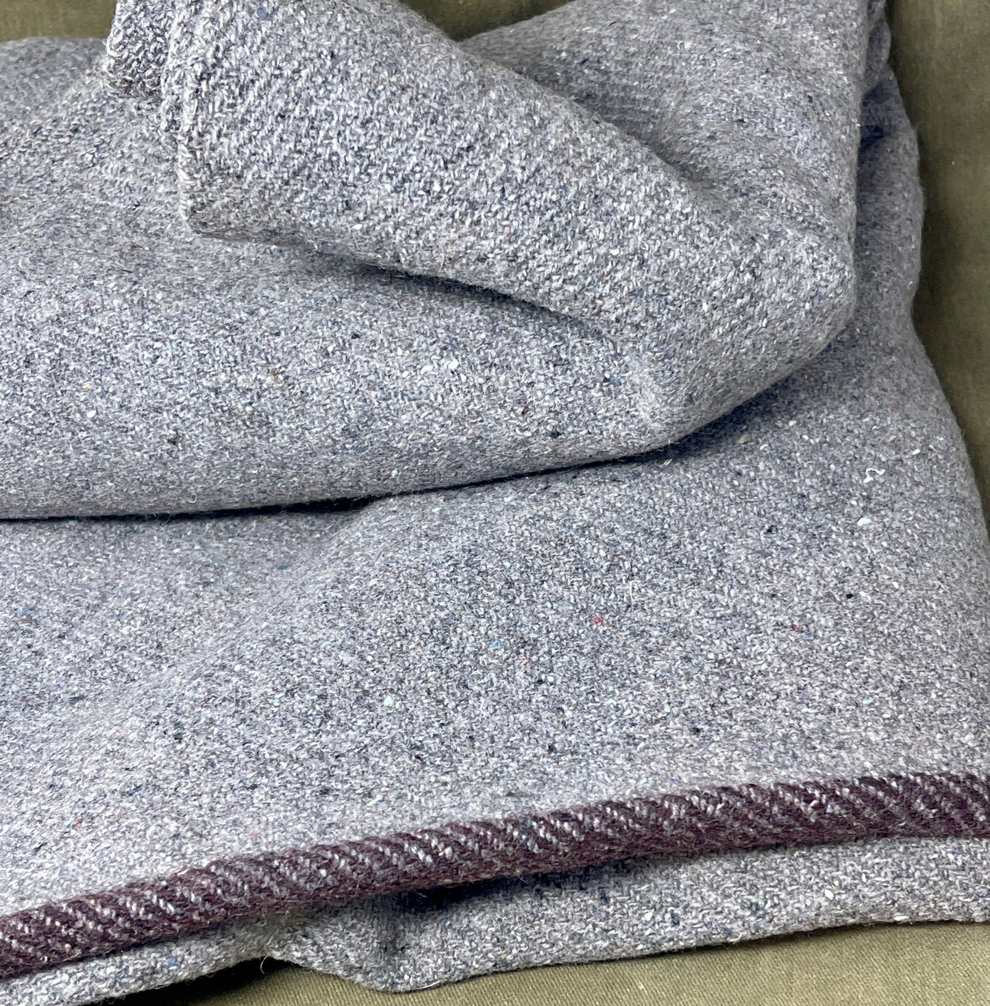 Gray textured fabric with a purple trim on a beige surface