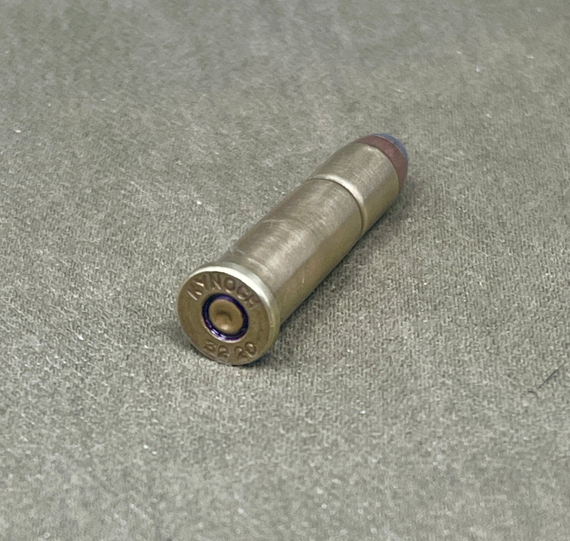 Metallic bullet casing on a textured gray surface