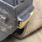 Close-up of a firearm magazine with a cartridge inserted, on a beige fabric background.