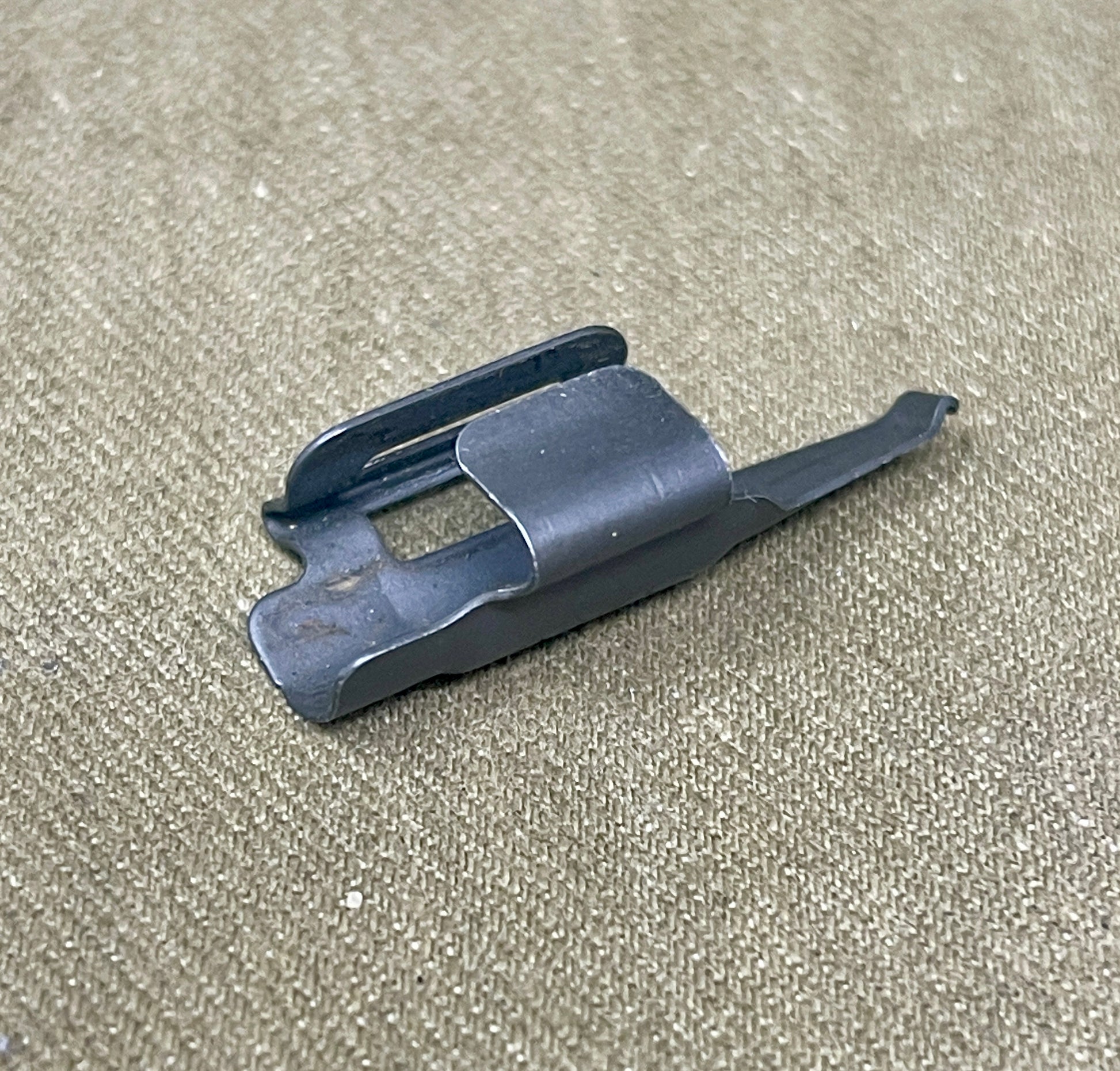 Black plastic component on a beige textured background