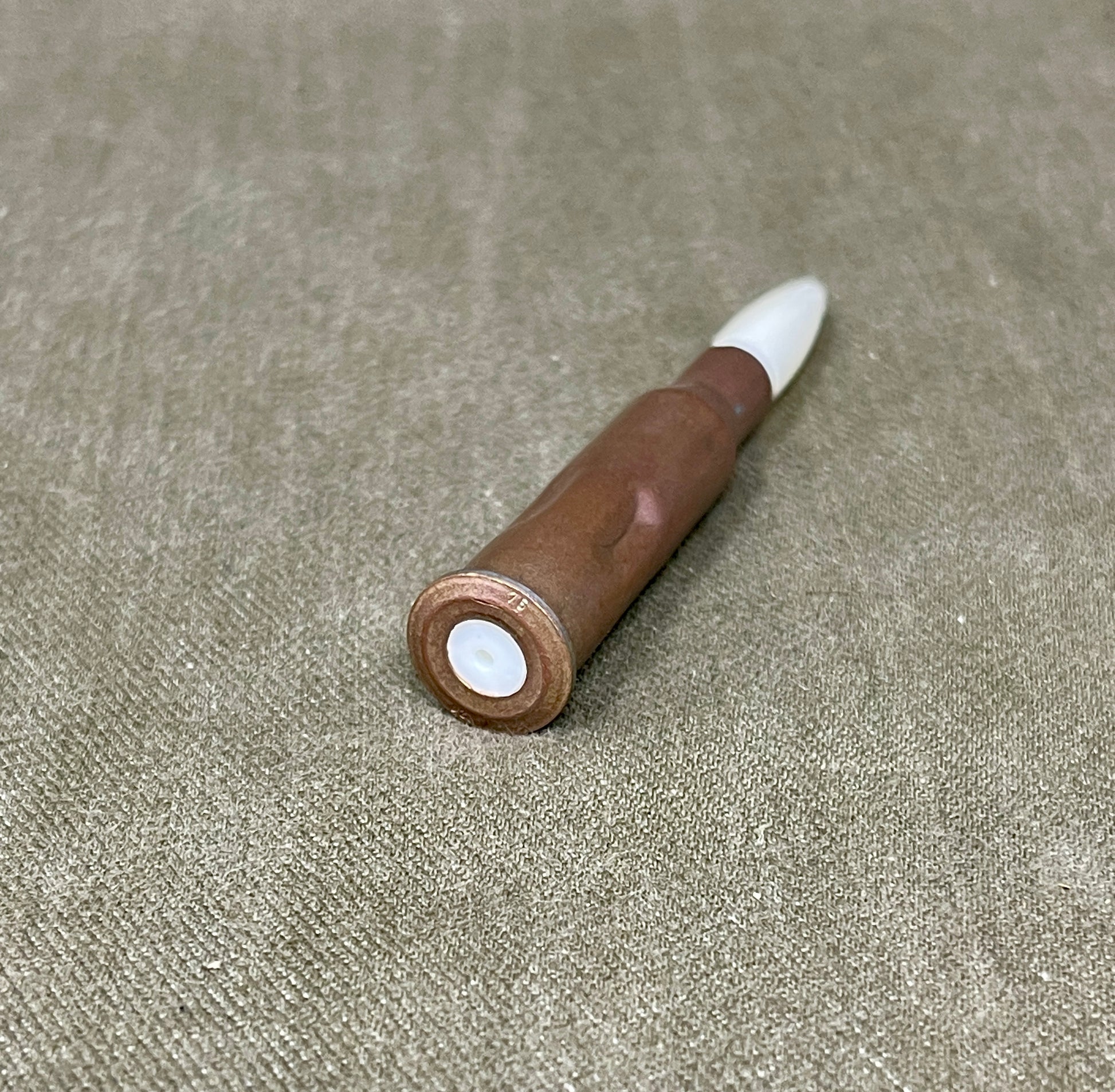 Wooden pen with white cap on a beige fabric background