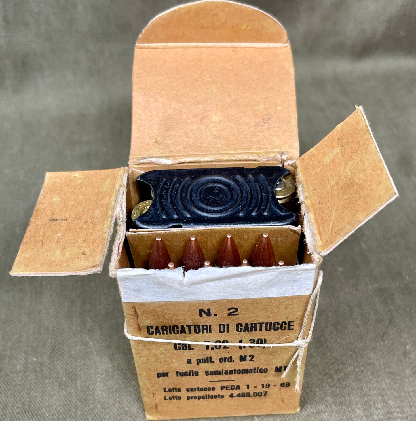 Open cardboard box containing ammunition on a gray background