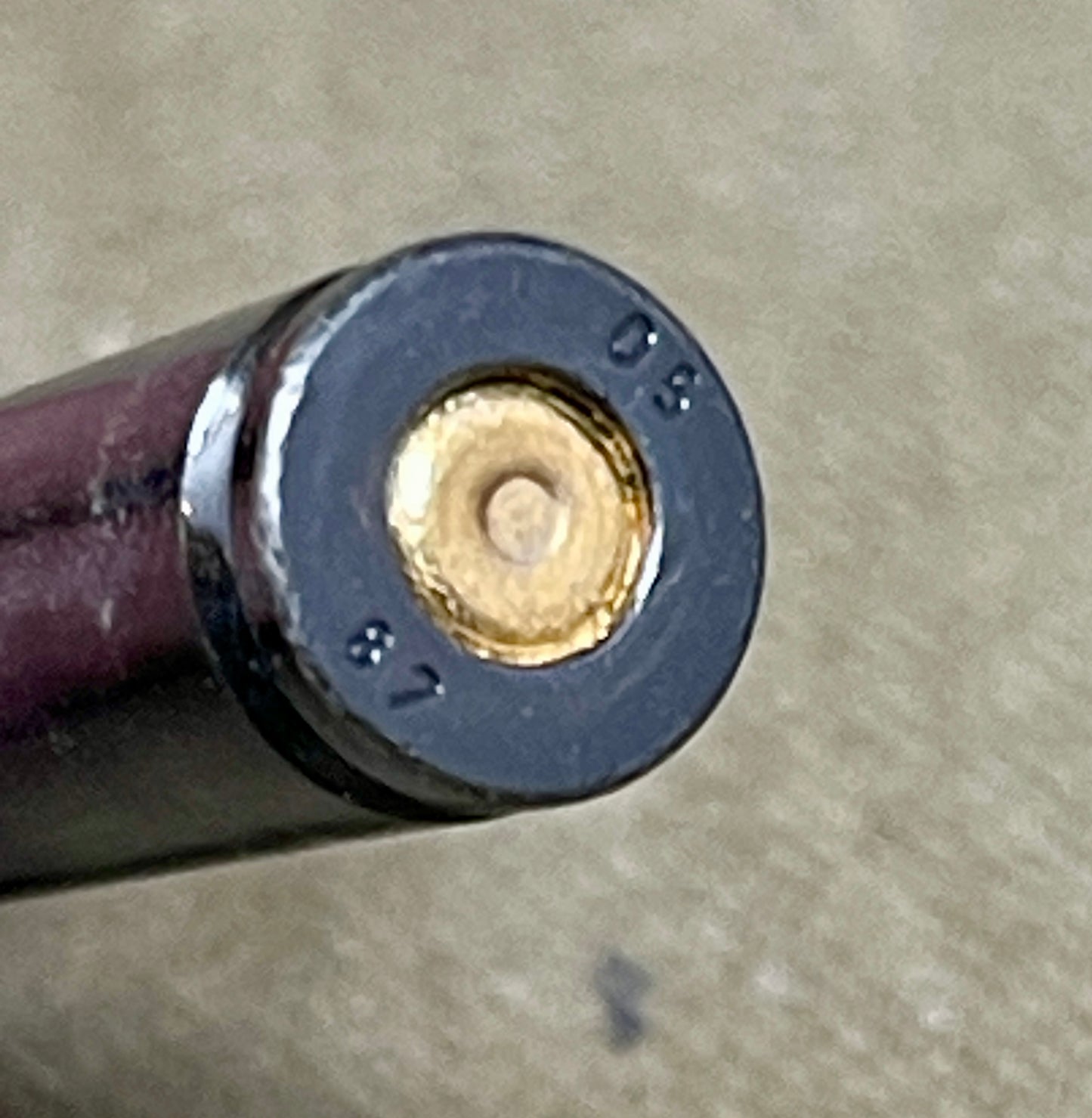Close-up of a rifle cartridge on a beige surface