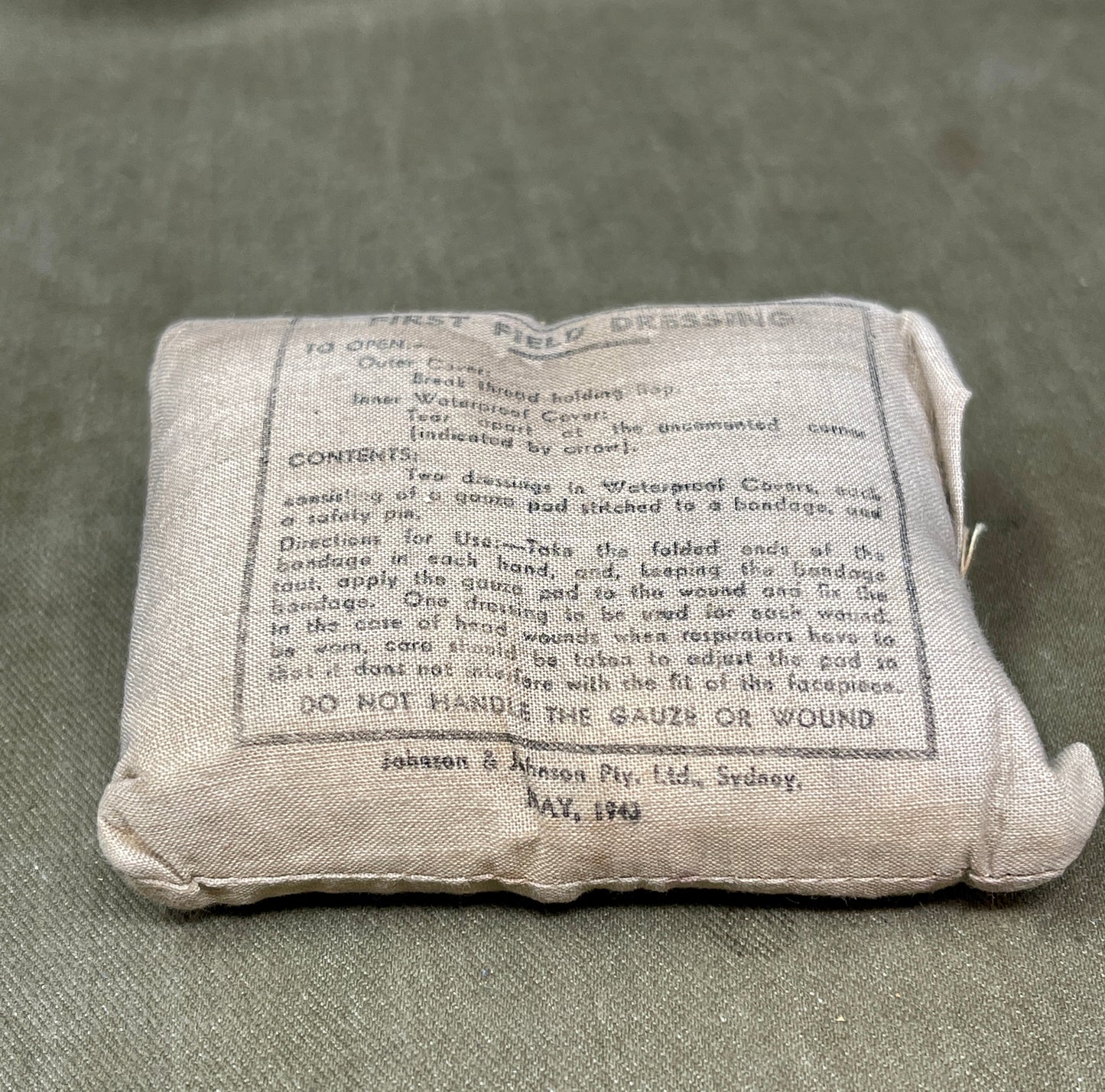 Vintage first aid dressing package with text on a gray background