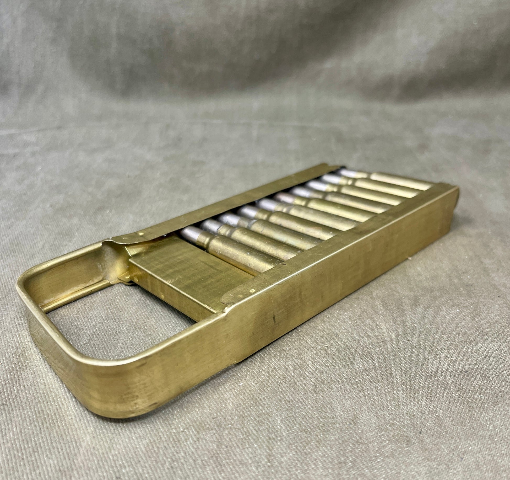 Brass pepper grinder with multiple nozzles on a gray fabric background