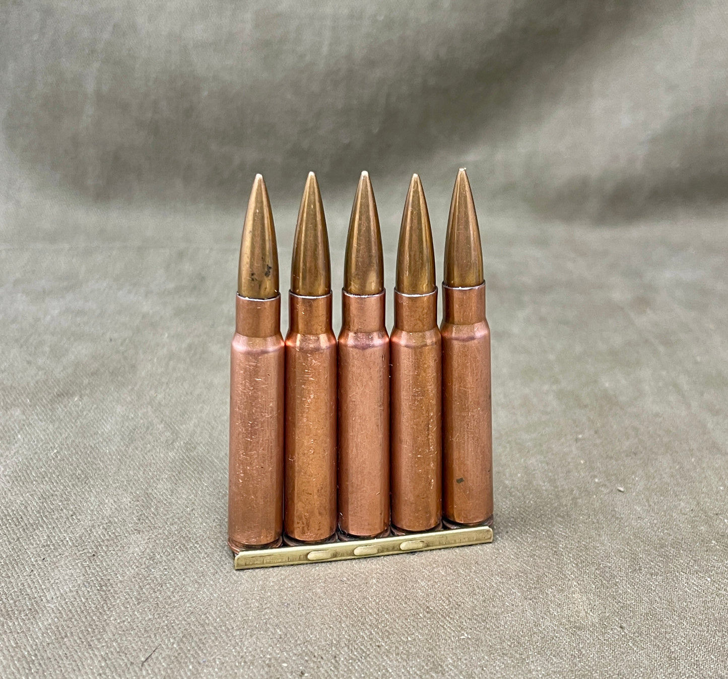 Five rifle cartridges on a textured gray surface