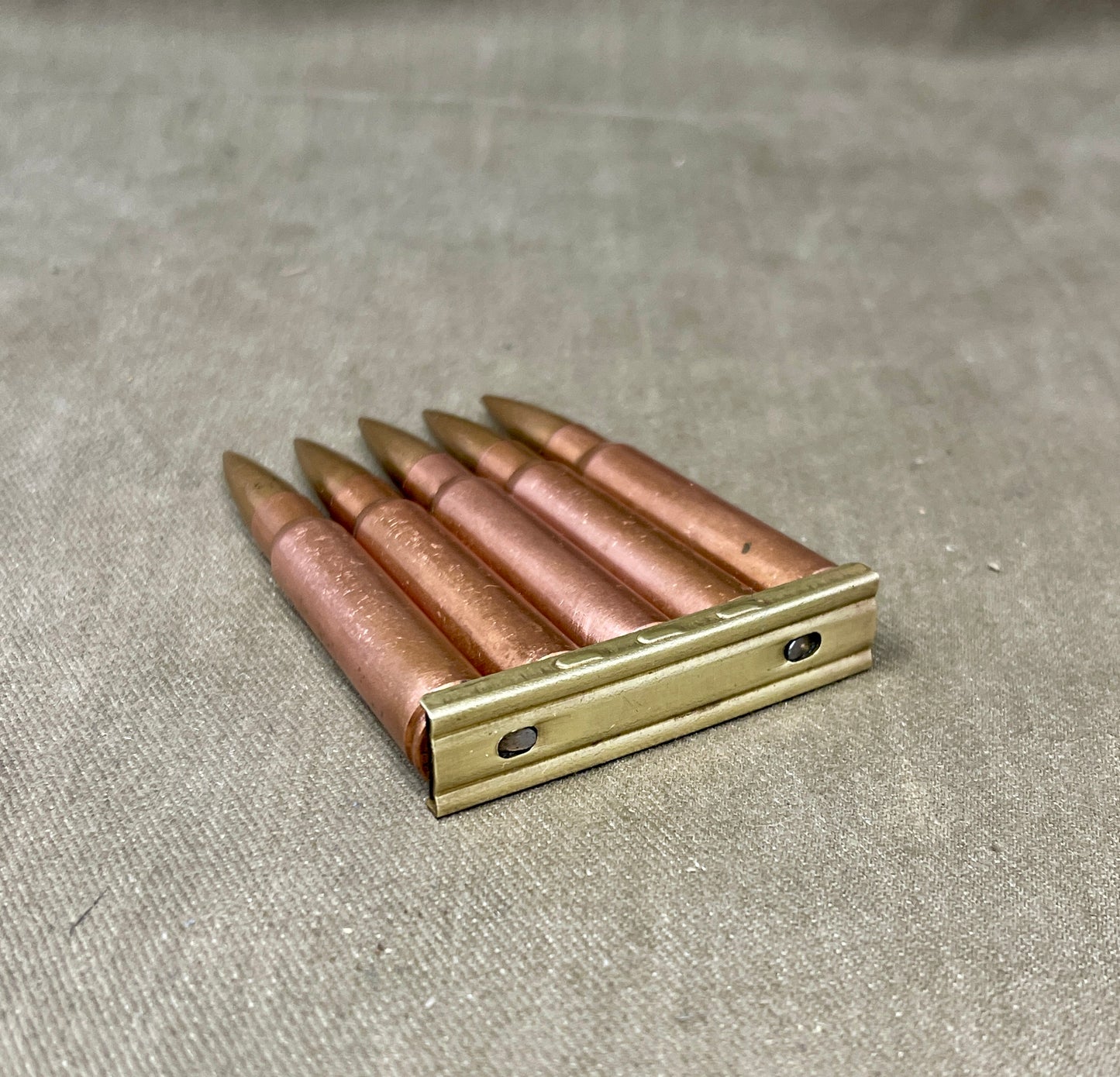 Metallic cartridge holder with bullets on a textured surface