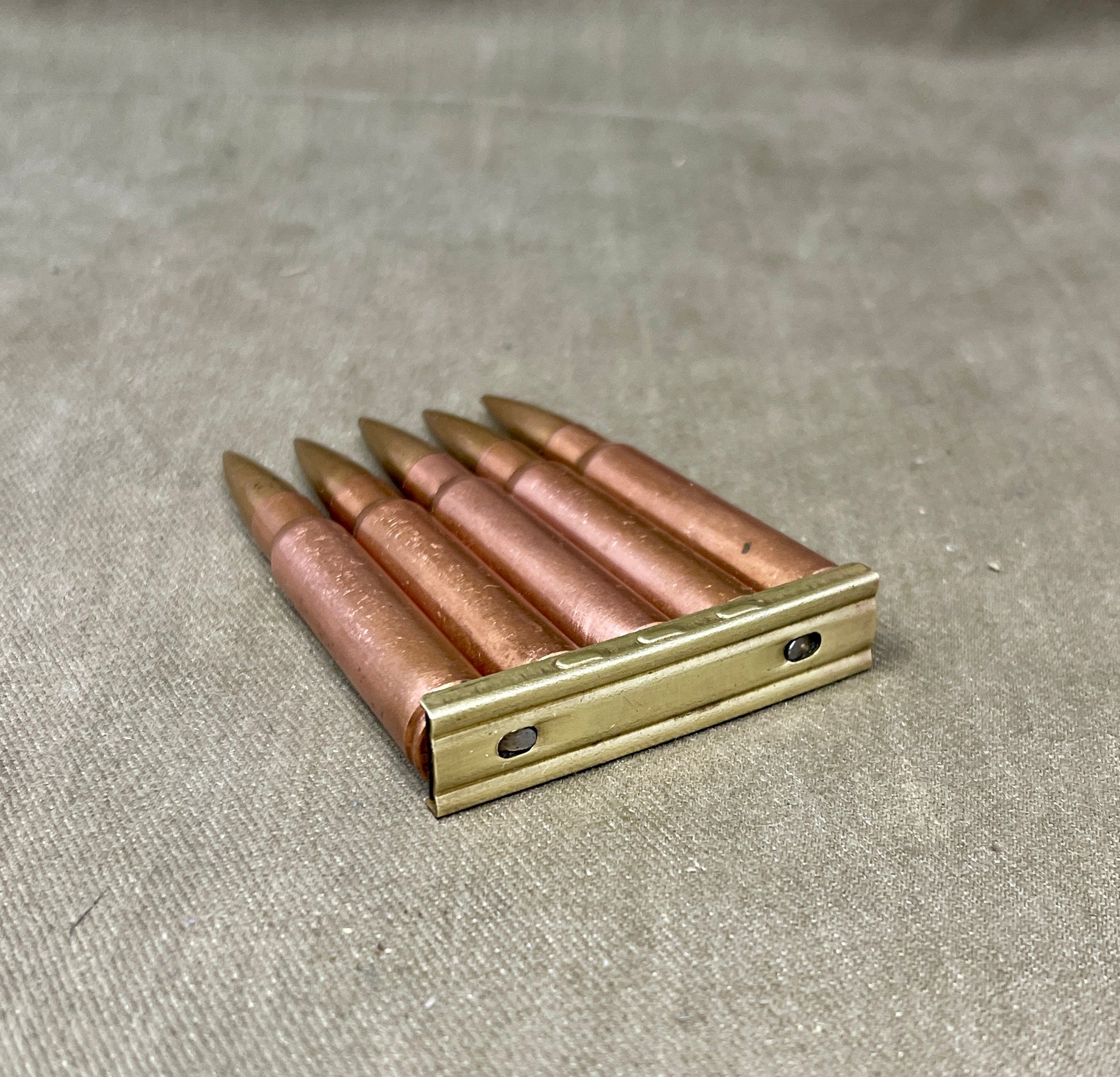 Metallic cartridge holder with bullets on a textured surface