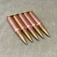 Five rifle bullets in a brass holder on a textured surface