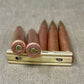 Five rifle cartridges on a metal holder against a textured gray background