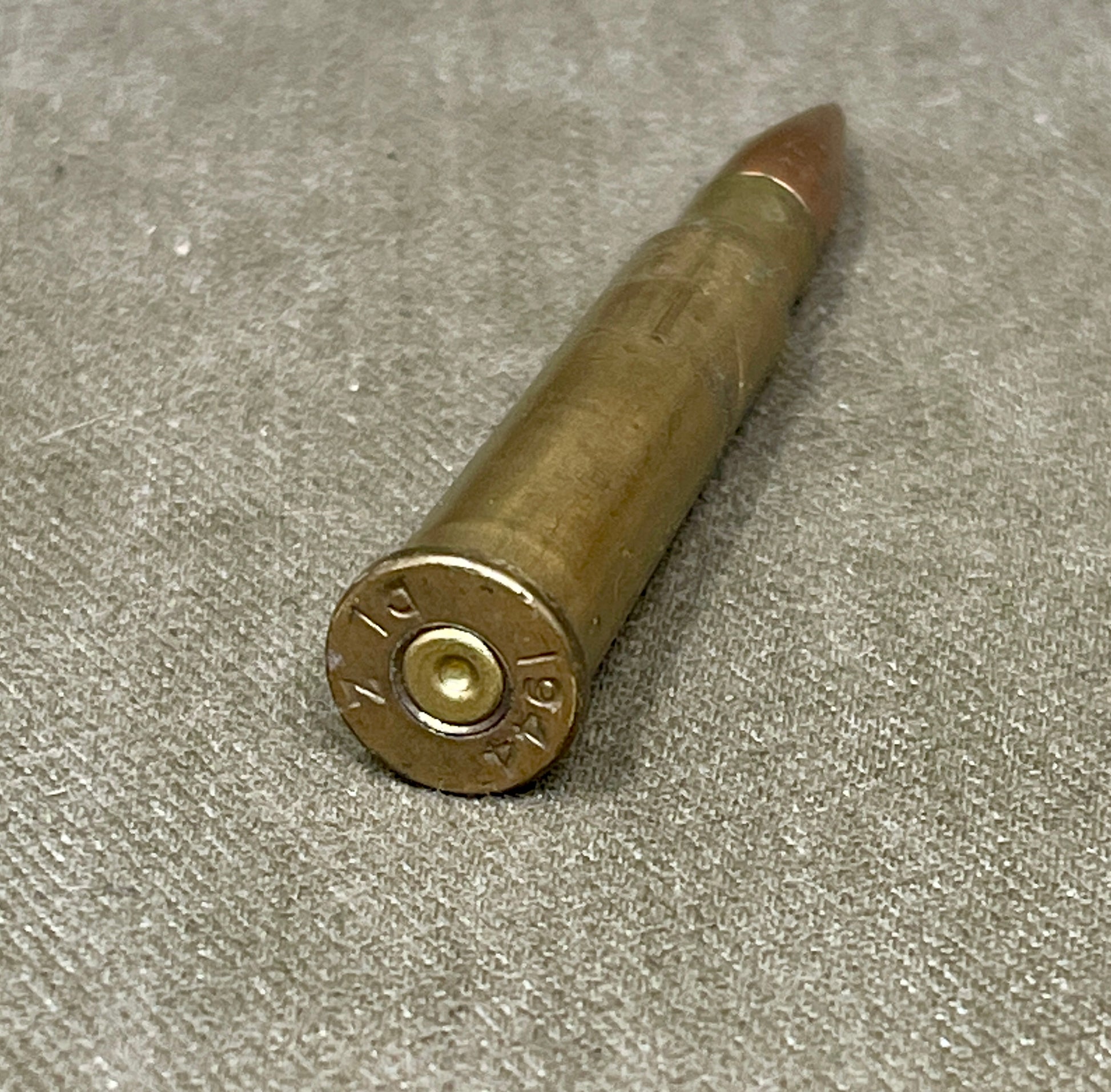 Bronze-colored bullet casing on a gray surface