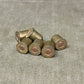 Set of six brass-colored ammunition casings on a gray fabric background