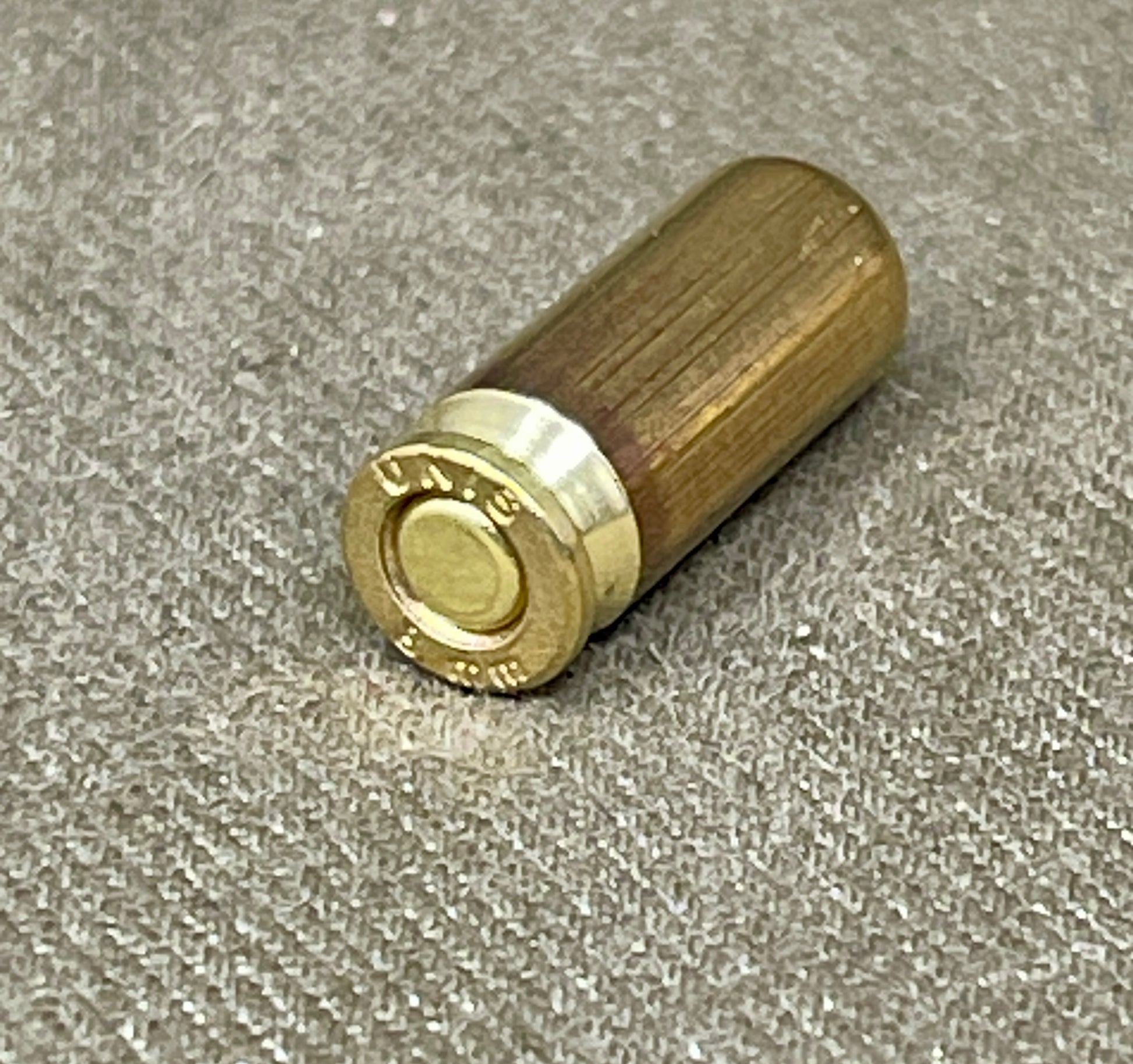 Wooden and brass cylindrical object on a textured gray surface