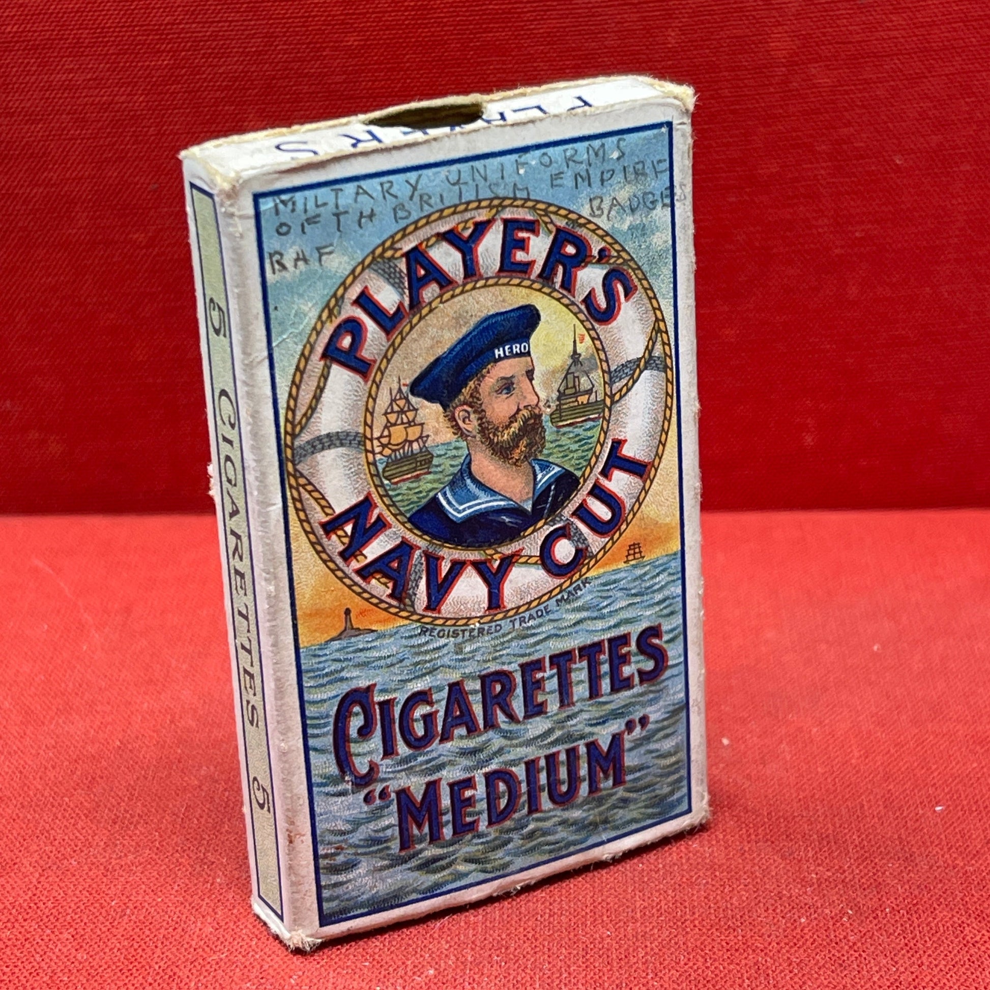 An empty packet for 10 Player's Medium Navy Cut cigarettes. The front has an ocean scene and a sailor framed in a life belt.