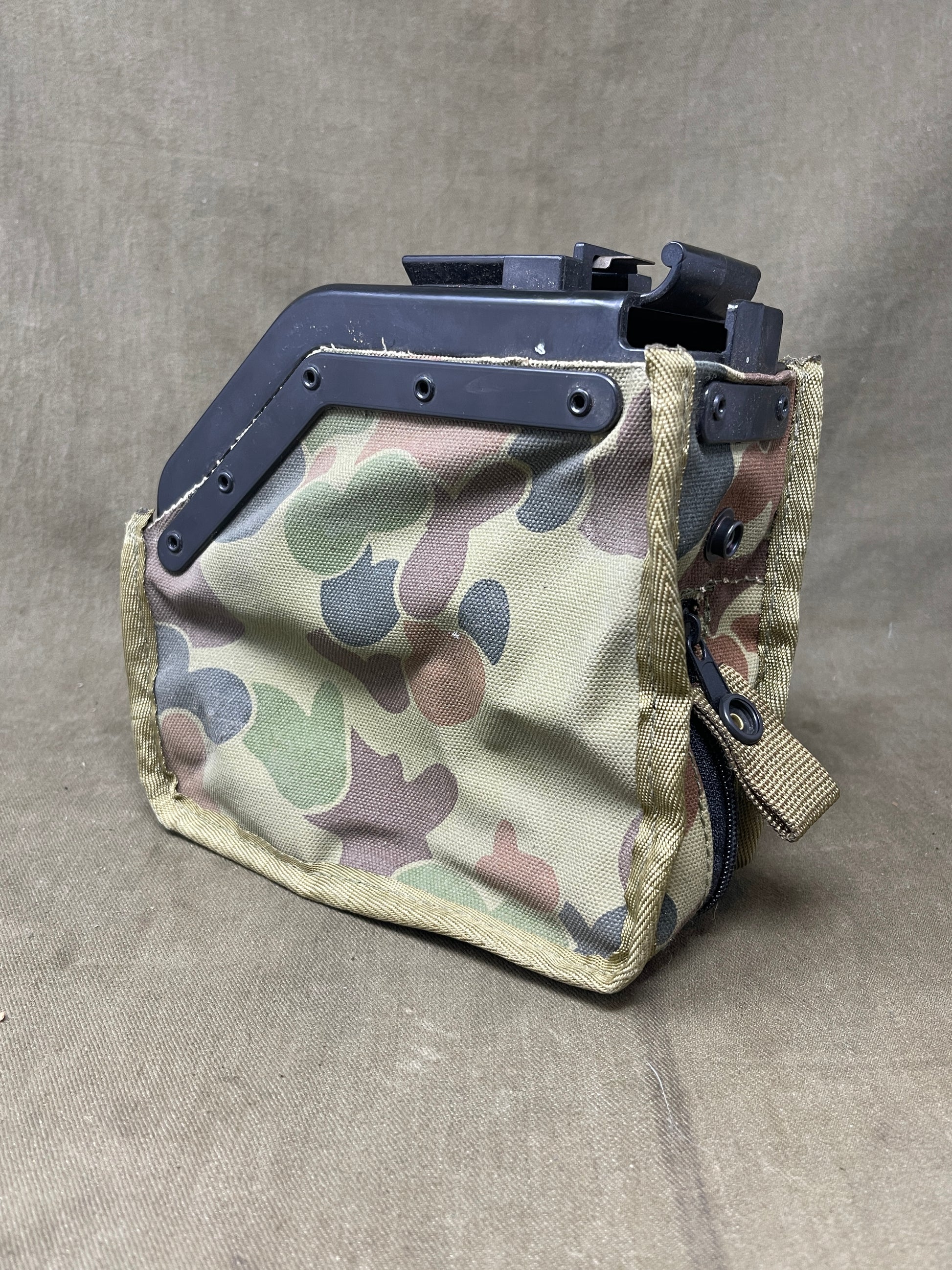 Australian Army LMG pouch, featuring the iconic Australian pattern camouflage. This pouch is designed for durability and functionality, constructed from rugged, heavy-duty materials capable of withstanding harsh field conditions. Its distinctive camouflage pattern ensures effective concealment across a variety of Australian terrains, including dense bushland and arid environments.