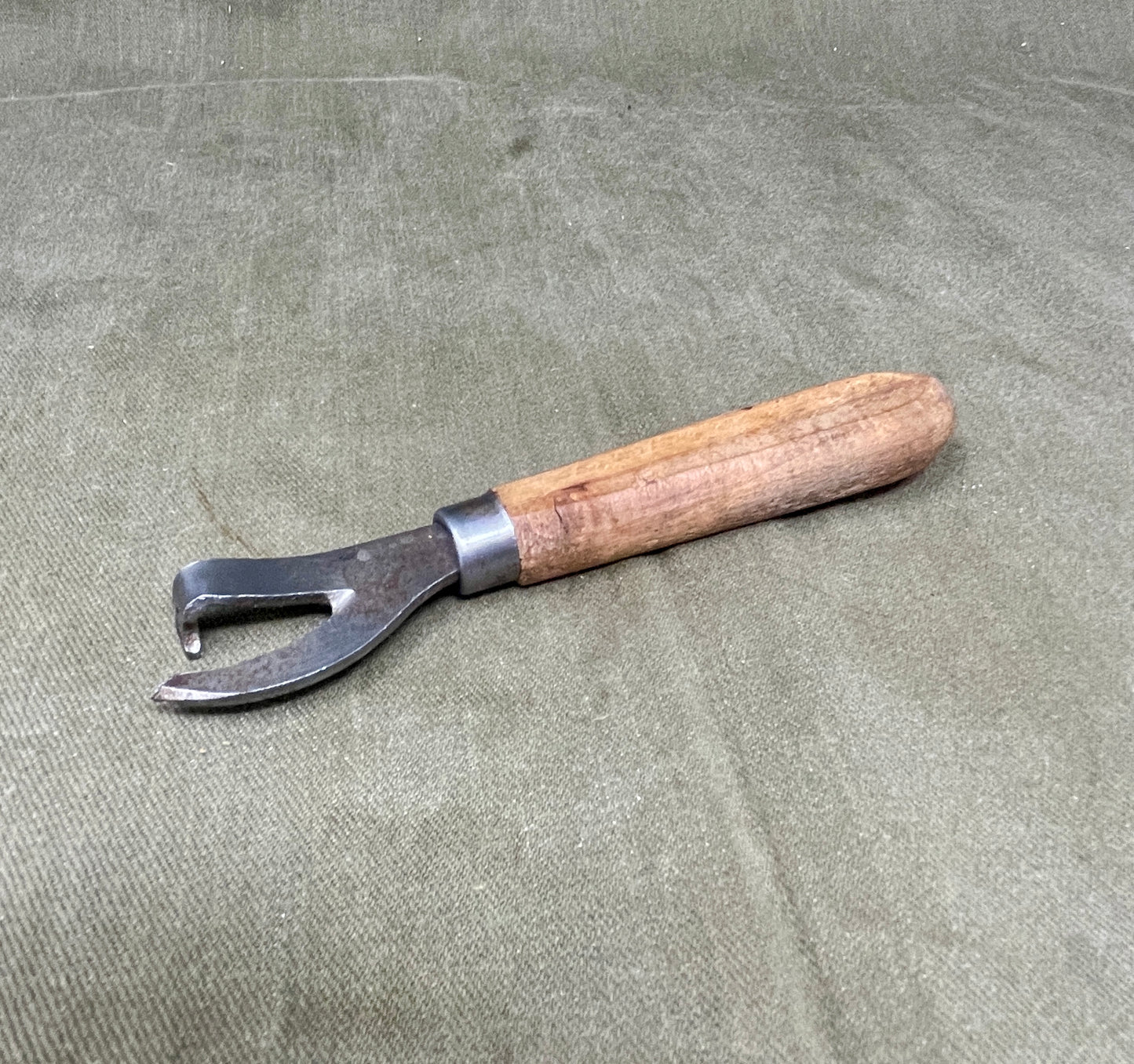 Authentic WWII German Wehrmacht can opener with original wood handle. A rare and practical piece of wartime field equipment for collectors and historians.

