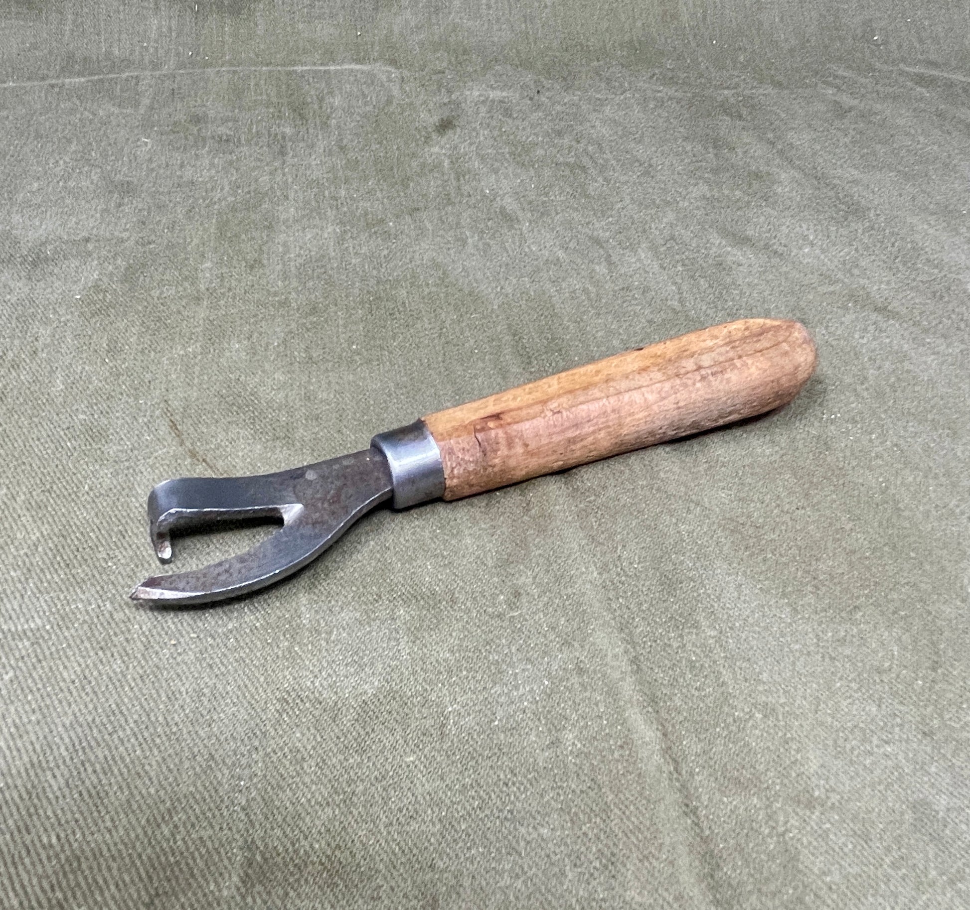 Authentic WWII German Wehrmacht can opener with original wood handle. A rare and practical piece of wartime field equipment for collectors and historians.

