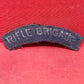 This original post-WWII Rifle Brigade shoulder title is a genuine piece of British military insignia, worn by members of the esteemed Rifle Brigade during the post-war period. Embroidered in white lettering on dark rifle green fabric, the title was typically stitched onto the upper sleeve of the battledress or service uniform. The Rifle Brigade, known for its distinguished service history and elite light infantry role, continued to uphold its proud traditions in the years following World War II. This should