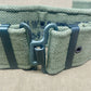 Green woven belt with a metal buckle on a beige surface