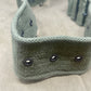 Green knitted headband with black buttons on a beige background