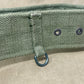 Close-up of a green belt with metal rings on a beige background