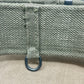 Close-up of a textured fabric surface with a metal ring attached, on a beige background.