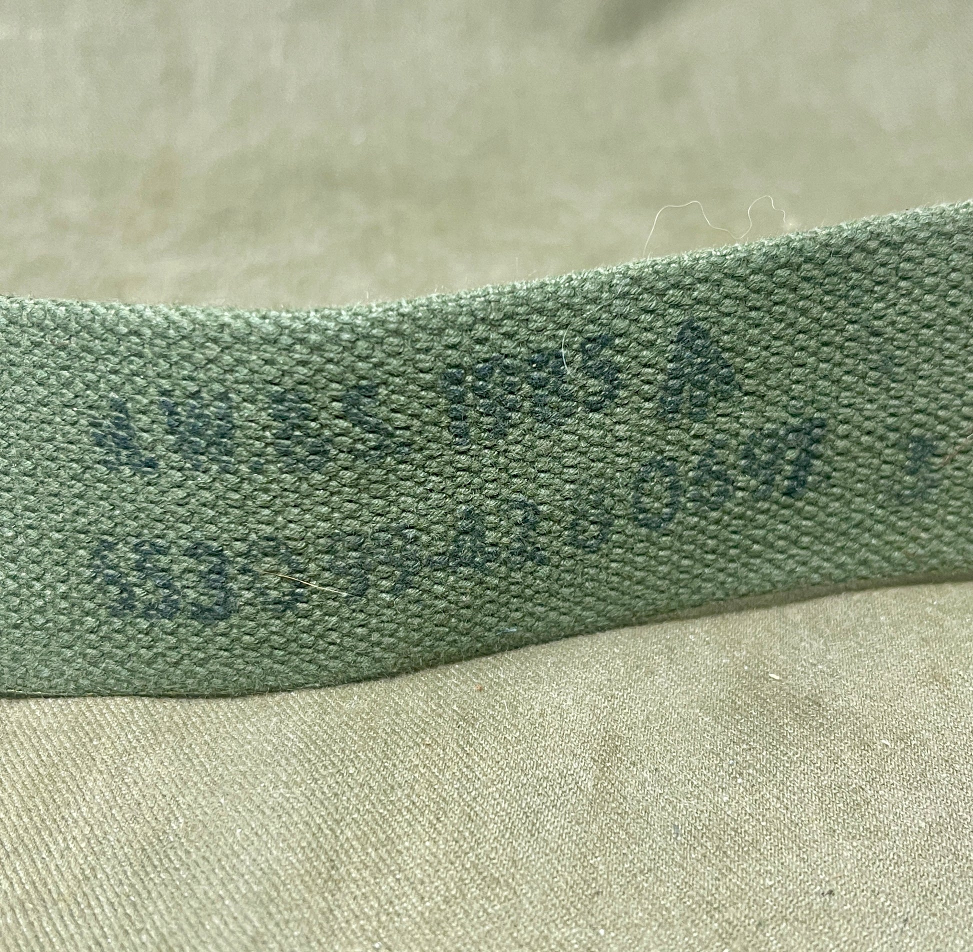 Close-up of a green fabric strip with visible texture on a beige surface