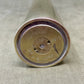 Close-up of a metallic cylindrical object with engraved text on a beige fabric background