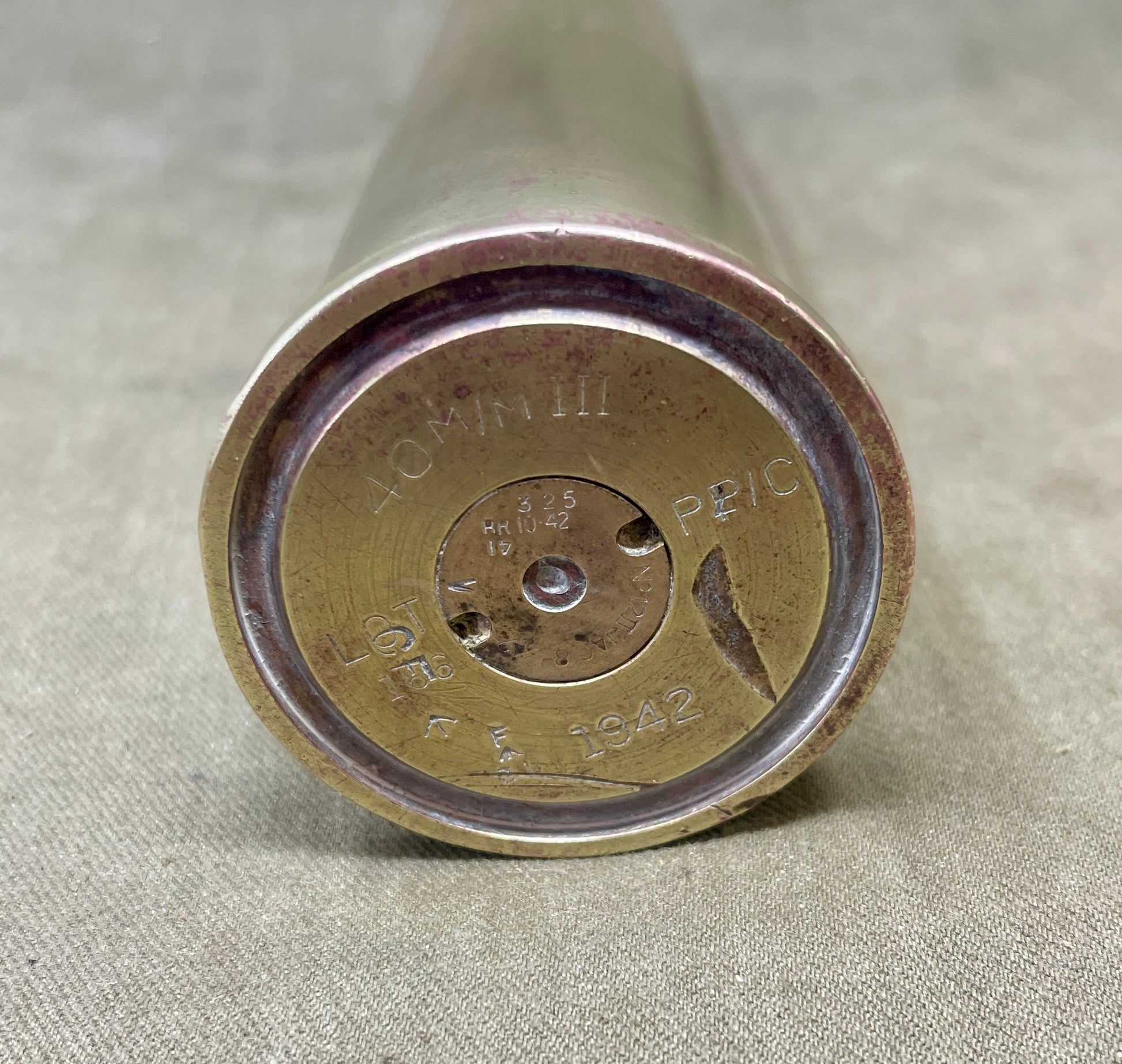 Close-up of a metallic cylindrical object with engraved text on a beige fabric background