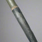 Close-up of a garden tool handle with a brand name on a concrete surface