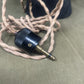 Close-up of a black audio cable connector on a beige cord against a gray background